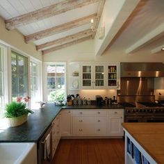 a large kitchen with wooden floors and white cabinetry, along with an island in the middle