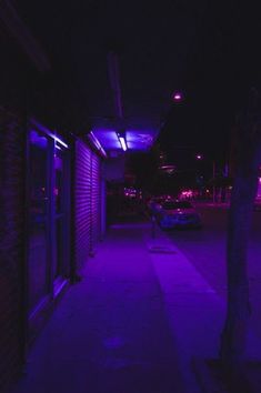 a purple light shines on the side of a building next to a parking lot