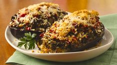 two stuffed eggplant halves on a plate with parmesan crumbs