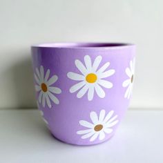 a purple cup with white daisies painted on it