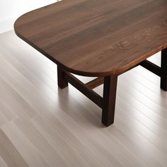 a wooden table sitting on top of a hard wood floor next to a white wall