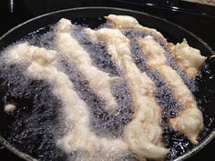 fried food being cooked in a frying pan on the stove top with oil and water