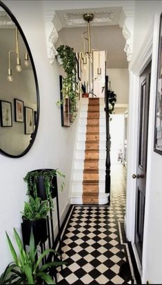 a hallway with black and white checkered flooring, potted plants and mirrors