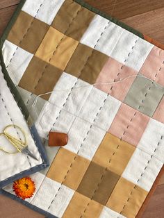 a pair of scissors and some fabric on a wooden table top with an orange flower