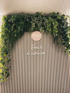 the wall is covered with green plants and white lettering