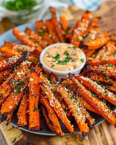 baked sweet potato fries on a plate with dipping sauce in the middle and garnished with parmesan sprinkles