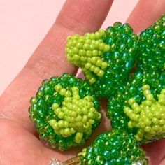 a person is holding some green beads in their hand and it looks like they are made out of plastic