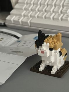 a lego dog sitting on top of a desk next to a keyboard