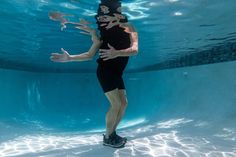 a man in black swimsuit under water with his arms out to the side and feet up