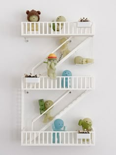 three shelves with stuffed animals on them in the shape of staircases, against a white wall