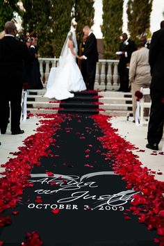 a wedding ceremony with red rose petals on the aisle