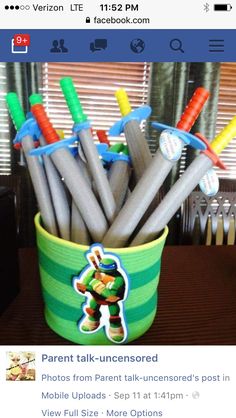 a green and white bucket filled with lots of plastic pens on top of a wooden table