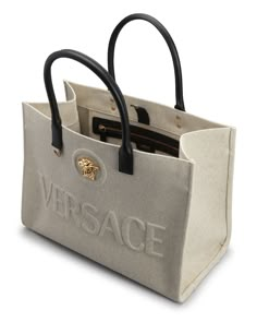 Versace canvas and acrylic tote bag with embossed logo and Medusa head accent     Rolled top handles     Open top with snap strap closure     Interior, one zip pocket    Approx. 11.4"H x 15"W x 7.4"D    "La Medusa" is made in Italy Expensive Purses, Versace Bag, Expensive Bag, Luxury Tote Bags, Trendy Purses, Luxury Bags Collection, Medusa Head, Women Purse, Stylish Handbags