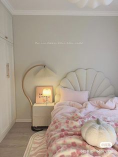 a bed with pink and white bedspread next to a lamp