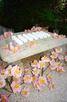 a wooden table topped with lots of pink flowers next to glasses and candles on top of it