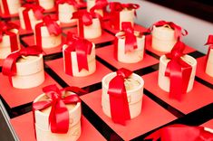 red and white boxes with bows on them sitting on top of each other in rows