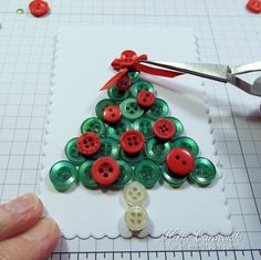 someone is making a christmas tree out of buttons on a piece of paper with scissors