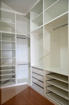 an empty walk in closet with lots of shelves and drawers on the wall, along with wood flooring