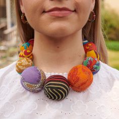 a woman wearing a multi colored necklace with balls on the front and back of her neck