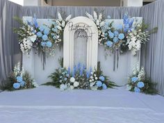 a white and blue wedding arch with flowers