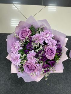 a bouquet of purple flowers sitting on top of a gray table next to a pair of scissors