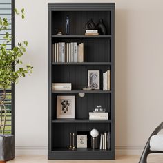 a black bookcase with many books on it and a plant in the corner next to it