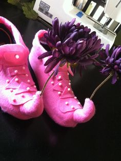 a pair of pink shoes sitting on top of a table next to a purple flower