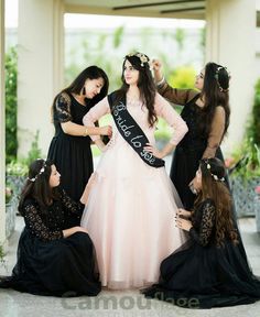 four women in black and pink dresses posing for the camera with one woman wearing a tiara