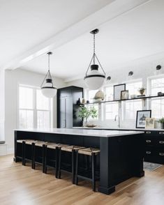 a large kitchen with black cabinets and white counter tops is pictured in this image, there are four stools at the center of the island