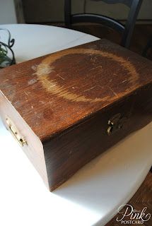 an old wooden box sitting on top of a white table next to a potted plant