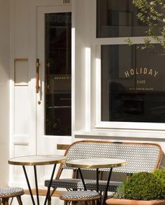 two tables and chairs sitting in front of a building with holiday cafe written on the window