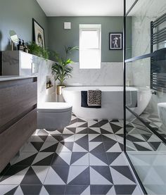 a modern bathroom with black and white tiles on the floor, tub, toilet and sink