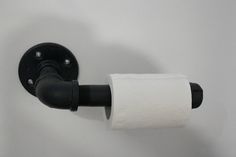 a toilet paper roll is hanging on the wall next to a black faucet