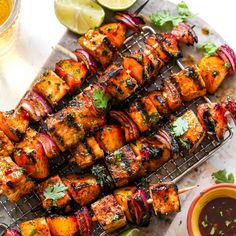 chicken kabobs on a grill with limes, cilantro and sauce