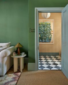 an open door leading to a living room with green walls and checkered flooring