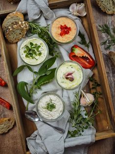 an overhead view of some food on a tray with spoons and bread in the background