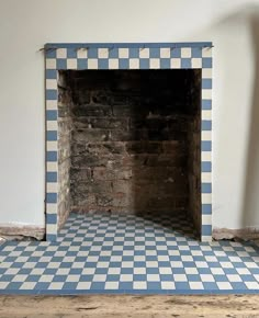 an empty fireplace with blue and white tiles on the floor