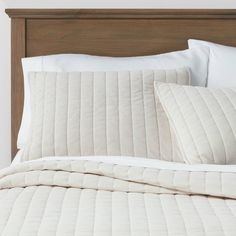 the bed is made with white linens and pillows, along with a wooden headboard