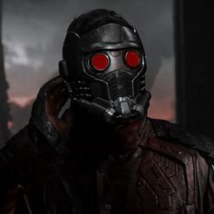 a man wearing a gas mask and holding his hand up to his face with red eyes