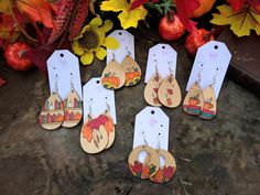 the wooden earrings are decorated with fall scenes and pumpkins, along with autumn foliage