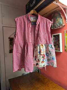 a red and white checkered shirt hanging on a wall next to a wooden table