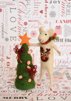 a small christmas tree next to a toy mouse and a stuffed animal on top of it