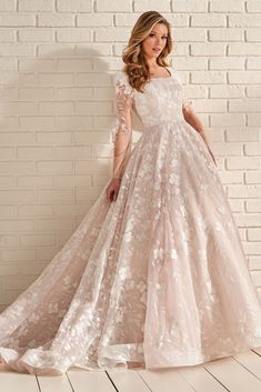 a woman in a wedding dress standing against a brick wall