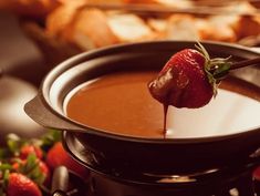 a strawberry being dipped into chocolate in a pot