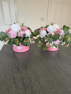 three pink and white flowers are in small vases on a counter top with green leaves