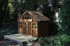 a small wooden shed sitting in the middle of a forest