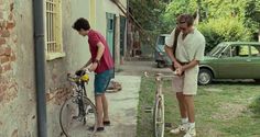 two men standing next to each other near a bike