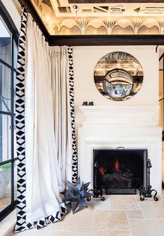 a living room filled with furniture and a fire place next to a window covered in curtains