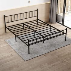 a metal bed frame sitting on top of a wooden floor next to a sliding glass door