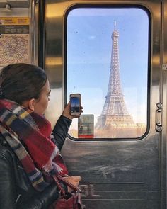 a woman is looking out the window at the eiffel tower